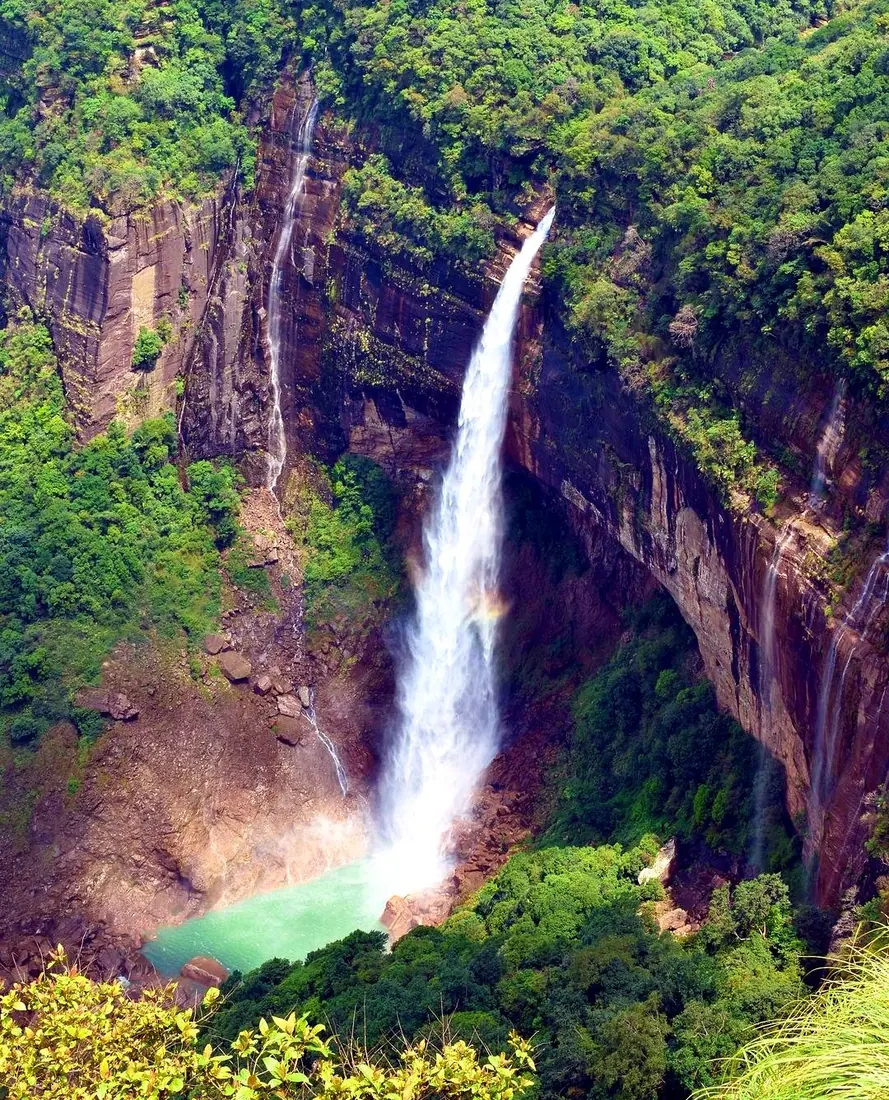 A tall waterfall dropping through a green cliff face near Sohra, Cherrapunji
