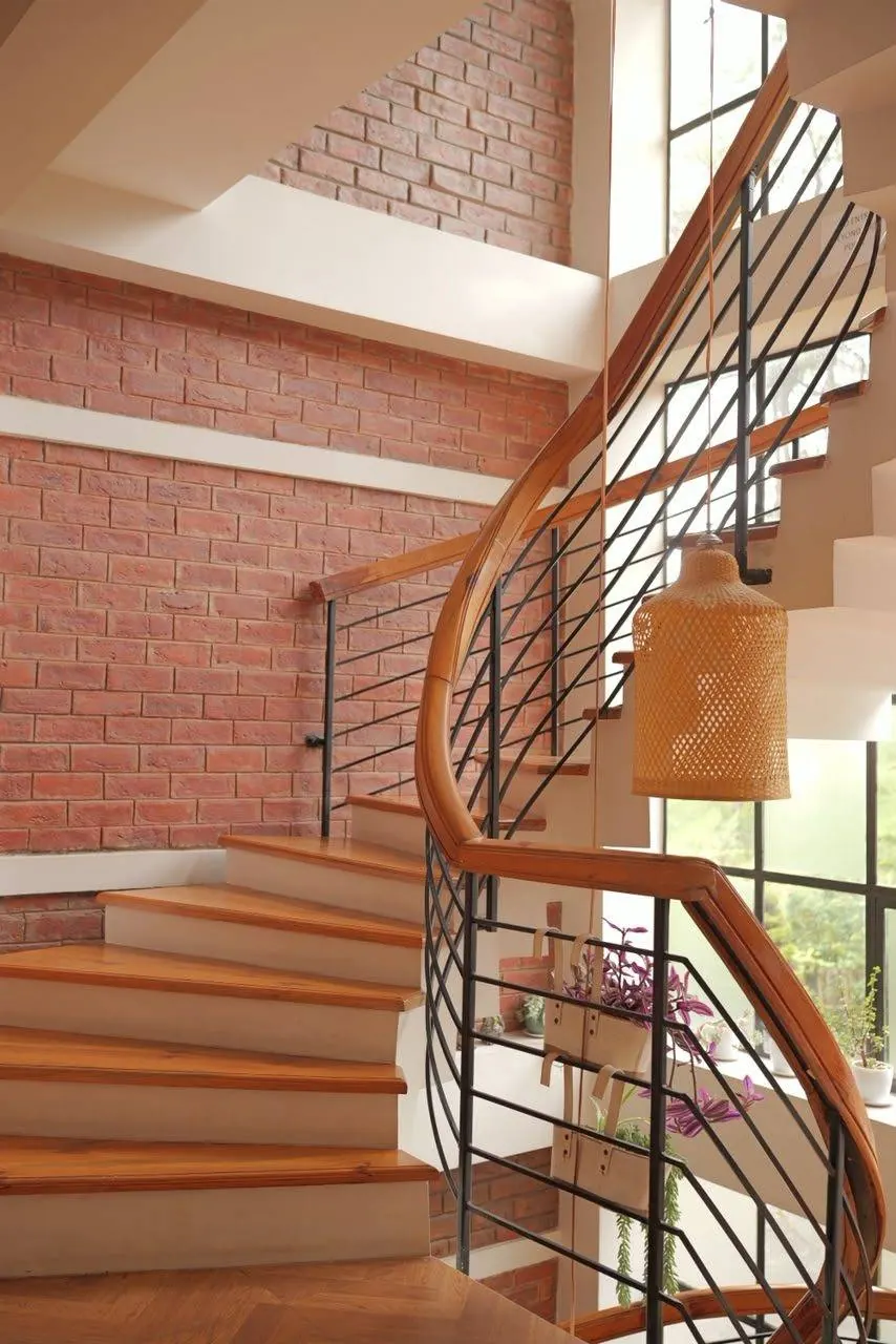 Staircase handrail detail, brick wall and hanging woven lamp